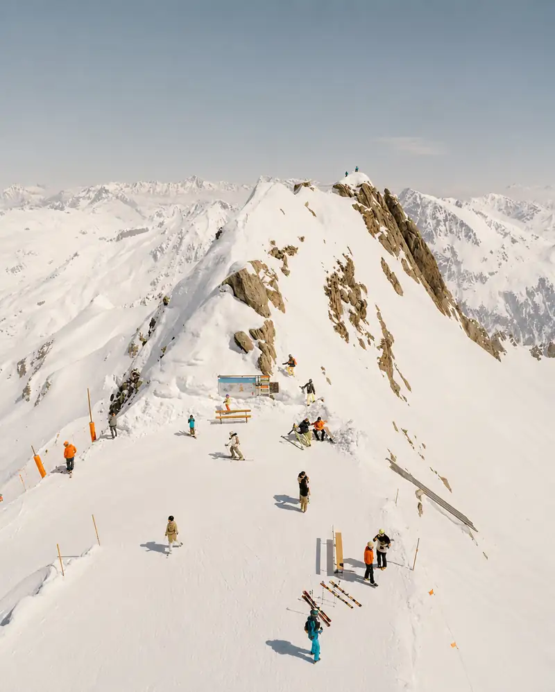 Skiërs op een smalle besneeuwde bergkam, van bovenaf gezien.