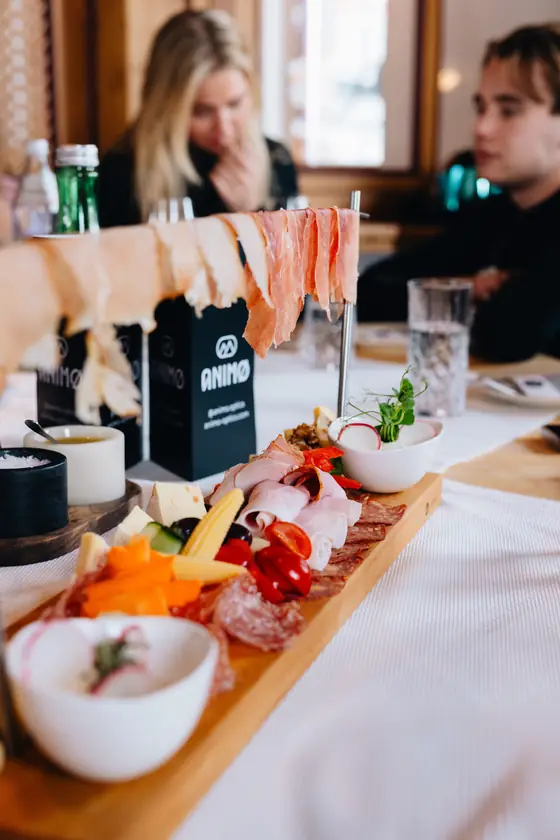 Een plank met charcuterie en kaas op een gedekte tafel in een berghut.
