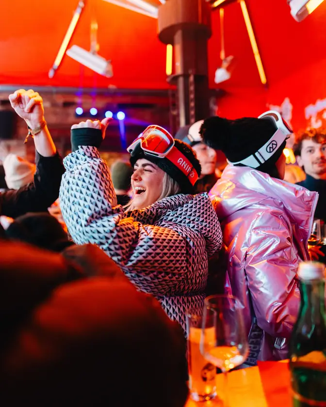 Een groep in skikleding op een feest in rood licht.