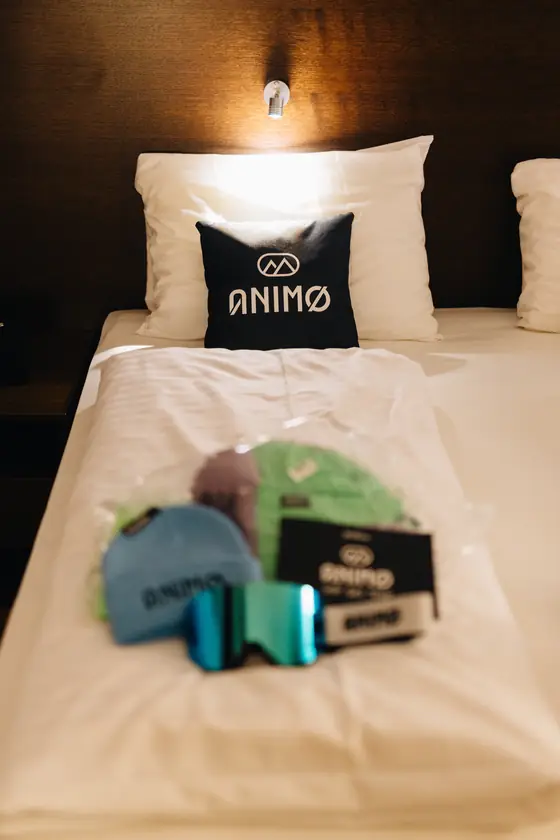 Een hoofdkussen met het Animo-logo en een goodiebag op een hotelbed.
