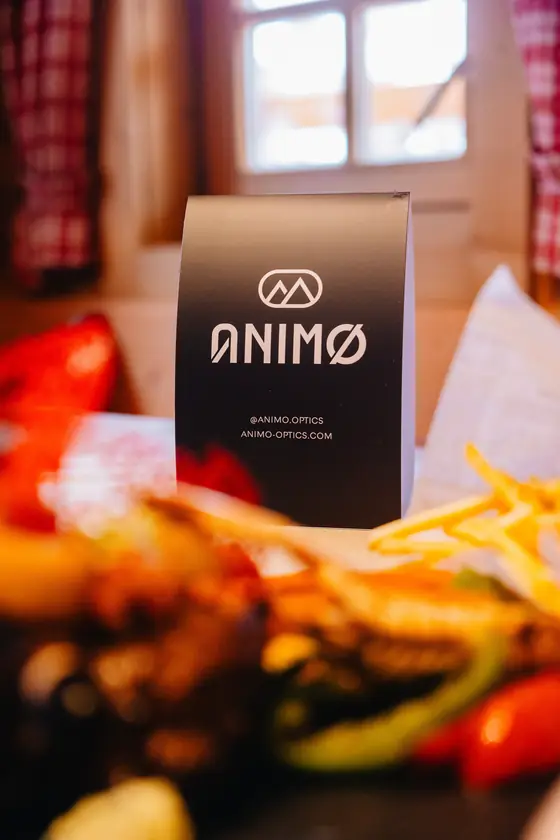 Een zwarte Animo-verpakking op een tafel naast friet in een berghut.