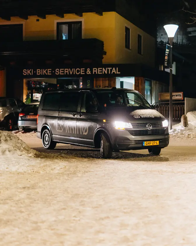 Een zwarte bus met Animo-goodies voor een skiverhuur, in het donker.