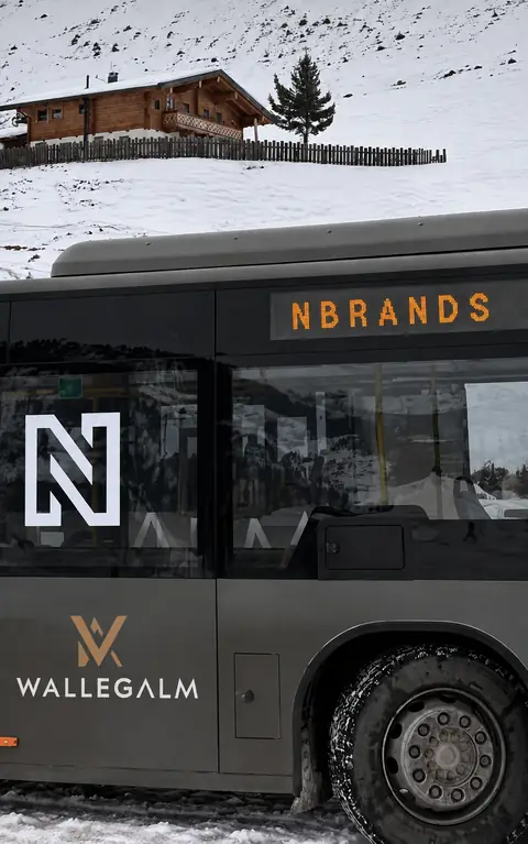 Een bus met het NBRANDS-logo langs een besneeuwde helling.